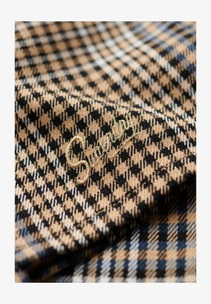 Gevlekt stof in zwart, beige en met een vleugje blauw; bevat gouden borduursels van "Superdry" op de oppervlakte.