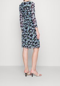 Schwarzes Blumenkleid mit langen durchsichtigen Ärmeln, das blaue Blumen und grüne Akzente aufweist. Weicher, leichter Stoff mit einem schwingenden Saum.