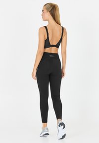 Svart sport-bh med justerbara band, i kombination med högmidjade svarta leggings. Leggingsen har en mjuk textur och en åtsittande design.