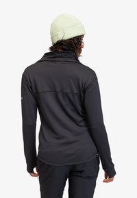 Black long-sleeve pullover with textured fabric and subtle lines, featuring a high collar and a light green knit beanie.