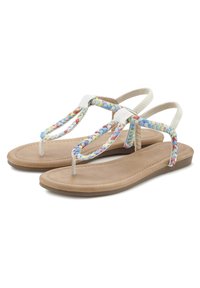 Flat sandals with a light brown sole, featuring multicolored braided straps and white accents. Simple, open design suitable for warm weather.