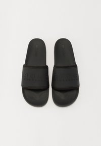 Black slider sandals with a thick strap featuring embossed "BORG STOCKHOLM" logo. Made of smooth rubber with a textured footbed.