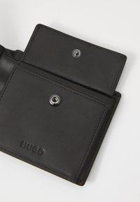Schwarze Lederbörse mit Druckknopfverschluss, ausgestattet mit einer glatten Oberfläche, geprägtem Logo und Kartenfächern innen. Einfaches, funktionales Design.