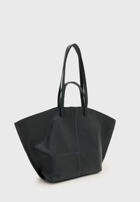 Didelė juoda odinė rankinė su struktūruotu dizainu, ilgomis plokščiomis rankenomis ir lygiu paviršiumi. Turi vientisą išorinę dalį ir minimalų dekorą.