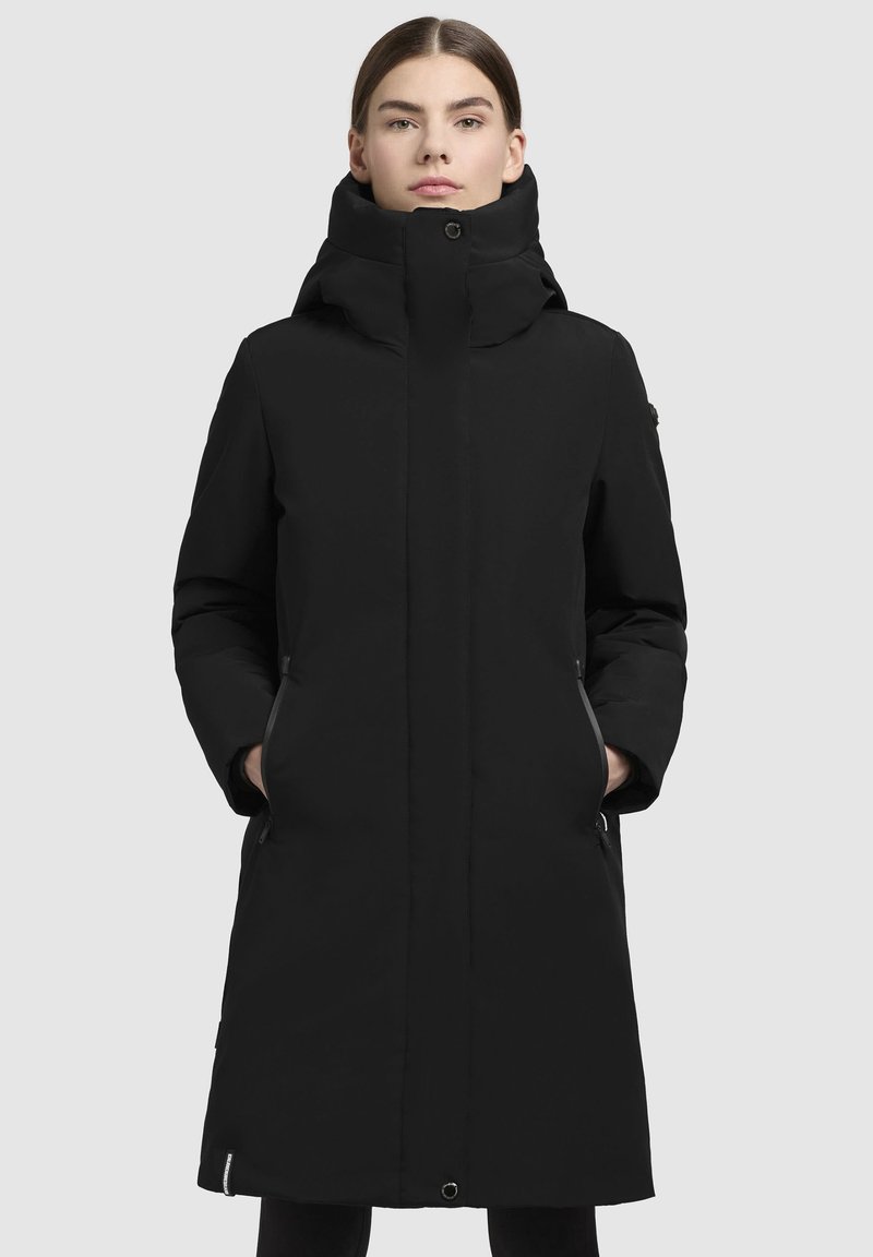 Manteau isolé noir avec un col haut, des poches latérales et une silhouette élancée. Présente une texture lisse et des accents de design minimalistes.