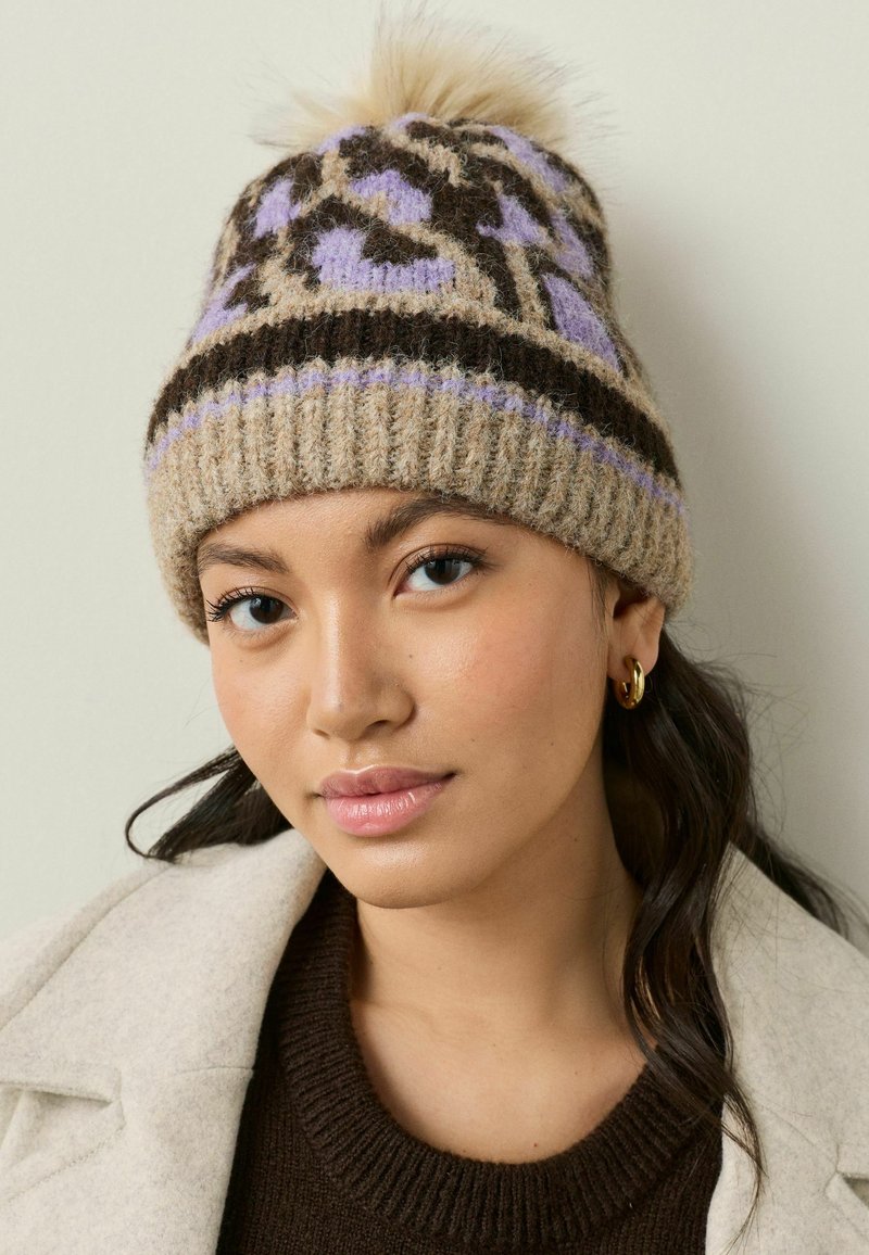 Knit beanie gaišā brūnā, brūnā un lavandas krāsā, ar rakstainu dizainu un pūkainu pom-pomu augšā. Ribota josla apakšā.