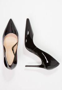 Svarta lackläder högklackade skor med spetsad tå och smal stilettklack. Slät yta och minimalistisk design.