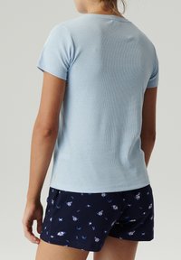 Jasnoniebieska koszulka z krótkim rękawem o prążkowanej strukturze, z okrągłym dekoltem, zestawiona z granatowymi szortami w motyw motyla.