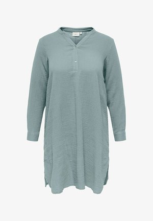 Gaiši zila tunika ar garām piedurknēm, strukturētu audumu, V veida izgriezumu, divu pogu aizdari un sānu šķēlumiem pie apakšmala.