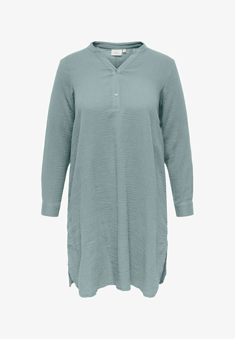 Šviesiai mėlynas ilgomis rankovėmis tunika su tekstūruota audinio, V formos iškirpte, dviejų mygtukų užsegimu ir šoninėmis prasišakojimais apačioje.