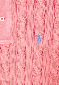 Sweter warkoczowy w jaskrawym różu, z wzorem o fakturze i małym niebieskim haftowanym logo. Z kontrastującym kołnierzem.