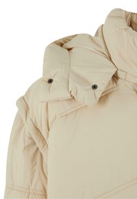 Beige puffer jacket featuring a high collar, buttoned flap, and diagonal stitching pattern; made from soft, lightweight material.