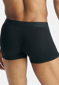 Svarta boxerkalsonger i ett slätt och stretchy tyg. Har en mjuk midjeresår och en strömlinjeformad passform, designad för komfort och täckning.