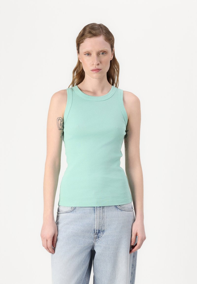 Mintgrønn ribbet tanktopp med rund hals og tettsittende design, sammen med lyseblå denimjeans. Ingen synlige mønstre eller maskinvare.