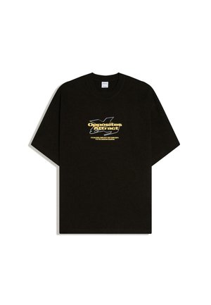Black short-sleeve T-shirt with yellow text "Opposites Attract" and smaller white text over abstract white line art on the chest.