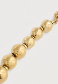 Zlatý náhrdelník s radom okrúhlych, lesklých perál s jemnými textúrami a malými oddelovačmi medzi každou perlou.