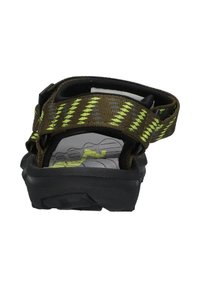 Bruine sandaal met gele accenten, verstelbare band en een gestructureerde rubberen zool. De achterkant toont een gevoerde binnenzool met groene logo-details.