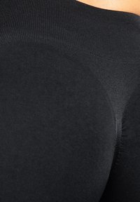 Zwarte leggings met hoge taille, gemaakt van rekbare, gladde stof. Voorzien van een naadloos ontwerp en een zachte textuur met subtiele accenten die de lichaamsvorm benadrukken.