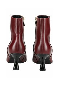 Botas de tobillo de cuero burdeos con un tacón negro afilado. Incluyen una cremallera lateral y tienen una textura suave.