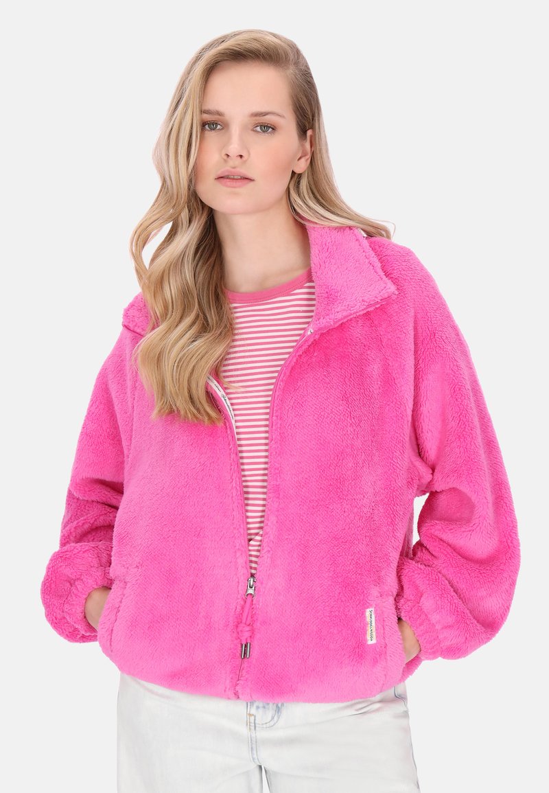 Leuchtend pinke Fleecejacke mit Reißverschluss, hohem Kragen und gerippten Bündchen, getragen über einem rosa-weiß gestreiften Hemd. Weiche Textur, oversized Passform.