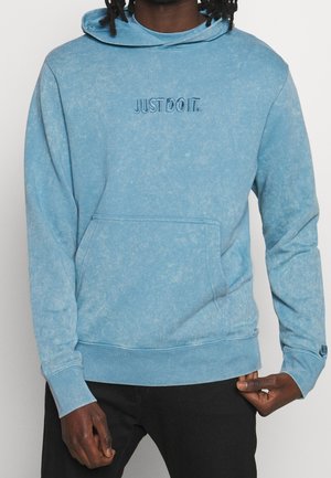 Sweat à capuche bleu clair avec une finition texturée, doté d'une poche avant et d'une broderie "JUST DO IT." sur la poitrine. Les poignets et l'ourlet sont côtelés.