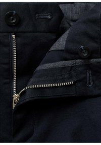 Črna denim jakna z gumbnimi zapiranji, srebrnimi zadrgami in sivim oblazinjenjem. Ima čiste šive in kontrastne teksture.