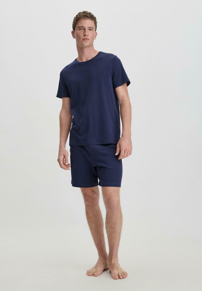 Kürzärmliges, dunkelblaues T-Shirt und passende Shorts aus einem weichen Stoff, mit einem einfachen, lockeren Schnitt, ohne sichtbare Muster oder Verzierungen.