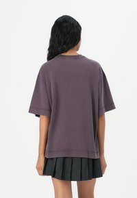 T-shirt oversized viola con maniche corte, realizzata in tessuto morbido, presenta una vestibilità comoda e semplici dettagli di cucitura sul colletto e sull'orlo.