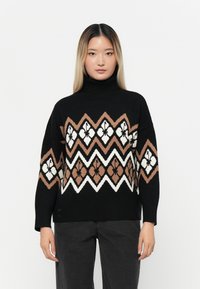 Schwarzer Rollkragenpullover mit einem geometrischen Muster in Braun, Weiß und Beige. Mit weitem Schnitt und lässiger Passform. Weicher Strickstoff.