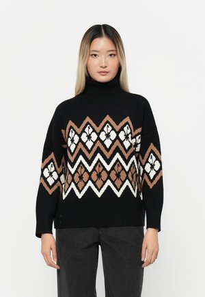 Pull col roulé noir avec un motif géométrique en marron, blanc et beige. Présente des manches larges et une coupe décontractée. Texture en tricot douce.