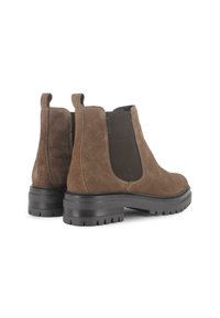 Botas de tobillo de ante marrón con paneles elásticos en los laterales, un tirador y suelas de goma gruesas y texturizadas para un mejor agarre.