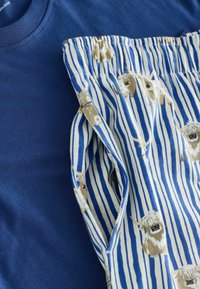 Marineblaues Baumwoll-T-Shirt kombiniert mit hellen Pyjamahosen mit vertikalen blauen und weißen Streifen sowie Cartoon-Tiermustern.