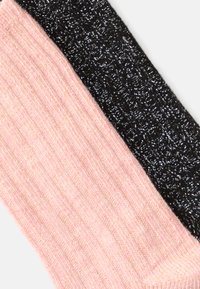 Duas meias texturizadas: uma rosa com nervuras e fios metálicos, a outra preta com um padrão tecido e brilhante.