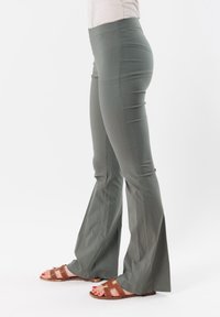 Pantaloni svasati a vita alta in tessuto verde oliva con una texture liscia. Presentano un design a gamba larga e si adattano comodamente alla vita.