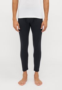 Schwarze Leggings aus einem dehnbaren Material, mit einem eng anliegenden Design, knöchellang und subtiler Markenkennzeichnung am Unterschenkel.