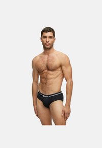 Mutande aderenti da uomo nere con fascia in vita bianca con logo. Tessuto liscio, taglio atletico e dettagli minimi.