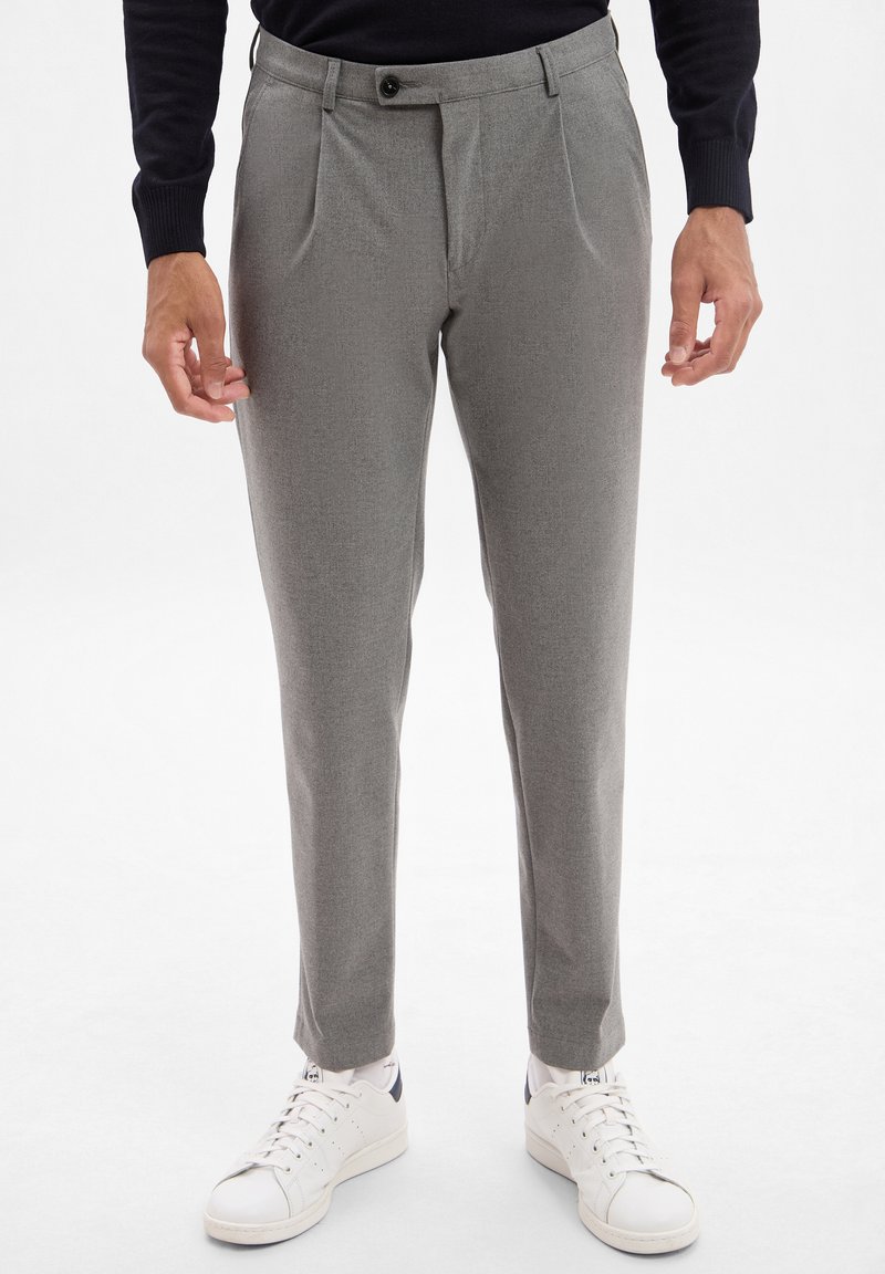 Gray trousers made of textured fabric, featuring a tailored fit, front pleats, and a flat front. Paired with white sneakers.