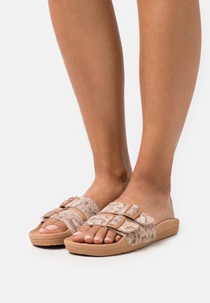 Sandales à enfiler avec un motif tissé beige, ornées de doubles boucles et dotées d'une semelle texturée. La semelle intérieure est rembourrée et légèrement surélevée.