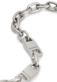 Collana di metallo con grandi anelli interconnessi e finitura argento opaco. Presenta una chiusura rettangolare con il nome del marchio inciso.