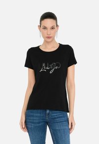 Zwart katoen t-shirt met een glanzend zilveren logo ontwerp op de borst. Korte mouwen en een ronde halslijn.