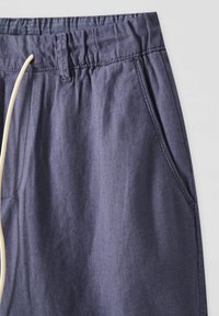 Pantalons en coton bleu marine avec une taille élastique, cordon de serrage réglable, poches latérales et une texture textile douce.