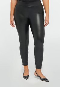 Zwarte faux leren leggings met een gladde, glanzende textuur, voorzien van een hoge tailleband en een slim-fit ontwerp, dat naar de enkels toe versmalt.