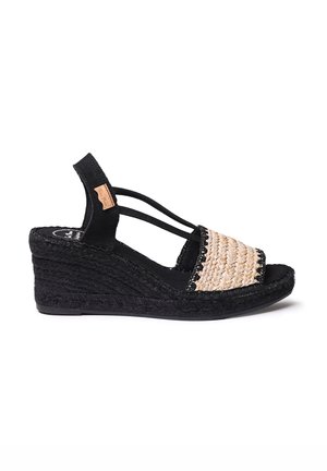 Svarta kilklackar med en vävd halmöverdel, elastiska tvärband och en strukturerad svart gummisul.