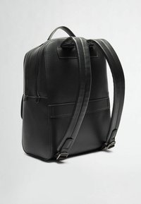 Zaino in pelle nera con finitura texture, due spallacci regolabili, manico superiore e scomparti con zip per il deposito.
