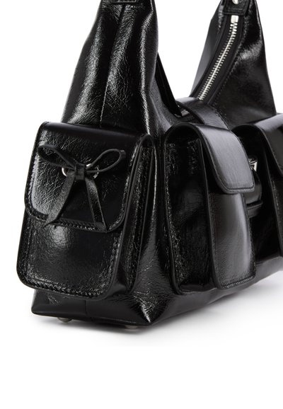 Borsa nera in pelle sintetica brillante, con più tasche frontali, ognuna dotata di una patta e un dettaglio a fiocco. Chiusura con cerniera lungo il bordo superiore.