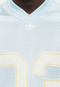 Γαλάζια φανέλα από δίχτυ που διαθέτει κίτρινο περίγραμμα και λευκούς αριθμούς "23", με μικρό λογότυπο Adidas στο στήθος.