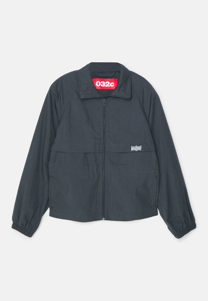 Sort zip-jakke med høj krave, med to frontlommer, elastiske manchetter og et rødt mærke indeni kraven.
