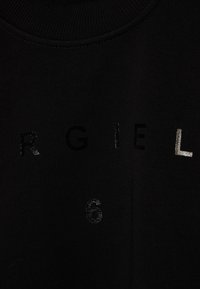 Felpa nera con il testo "ARGIEL" in diverse font e texture, con il numero "6" in un motivo sottile. Collo a costine.