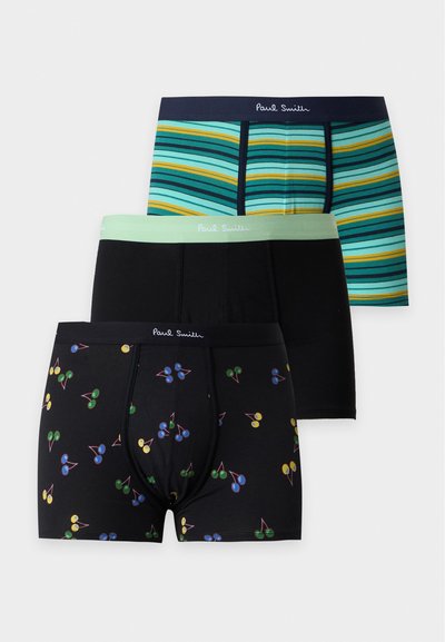 Trois paires de boxers Paul Smith : une avec des cerises multicolores sur fond noir, une noire unie avec une ceinture menthe, et une avec des rayures bleues et jaunes.