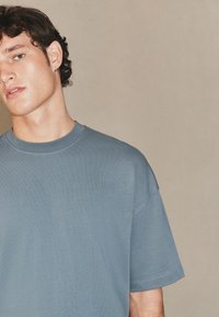 Tricou albastru deschis cu mânecă scurtă realizat din material moale, cu decolteu rotund și detalii minimale la cusături. Design simplu și casual.